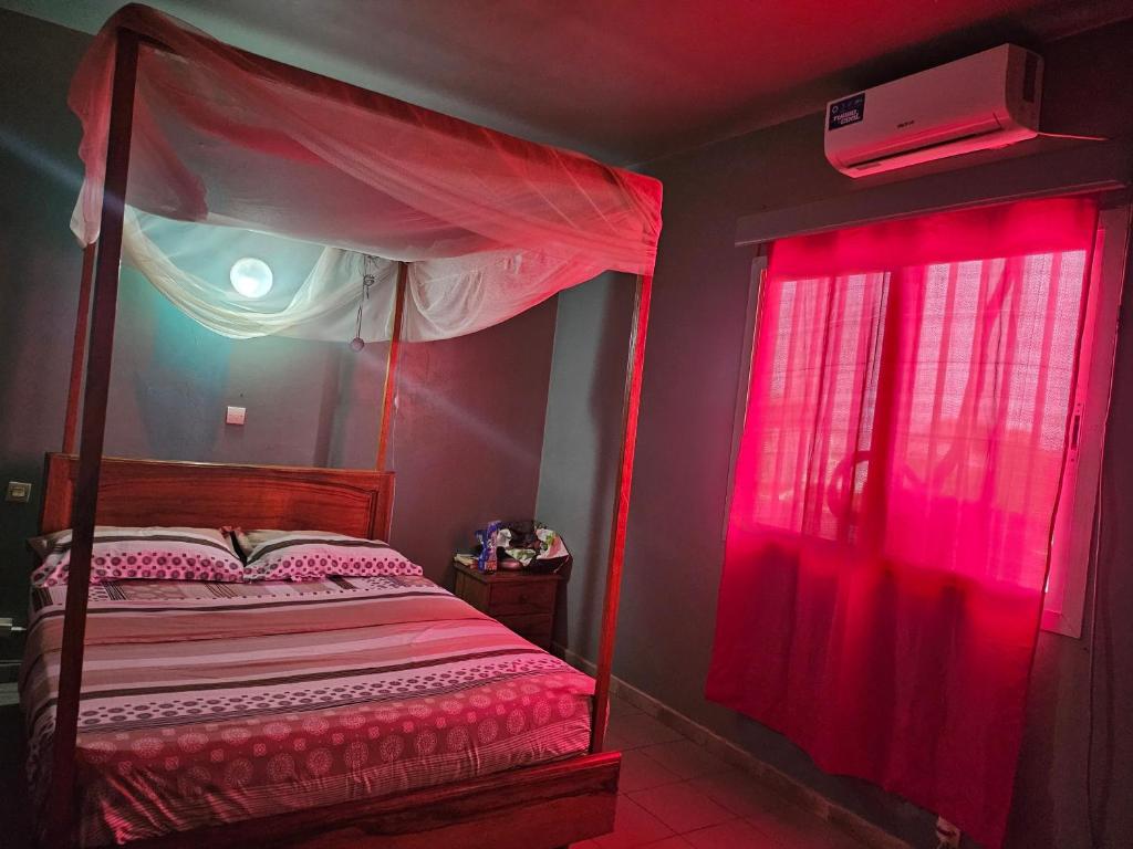 a bedroom with a bed with red curtains and a window at Villa Duchesse in Sali Nianiaral