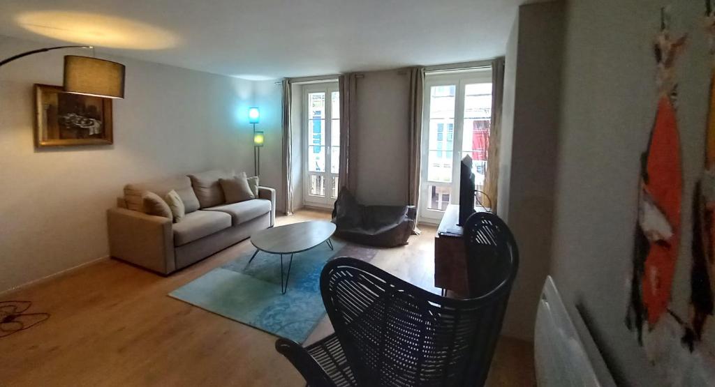 una sala de estar con un sofá y una mesa en Burdigala Homes - Appart du Jardin Public, en Burdeos