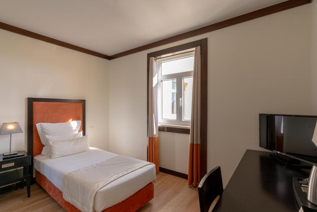 a hotel room with a bed and a window at Hotel Inglaterra - Charme & Boutique in Estoril
