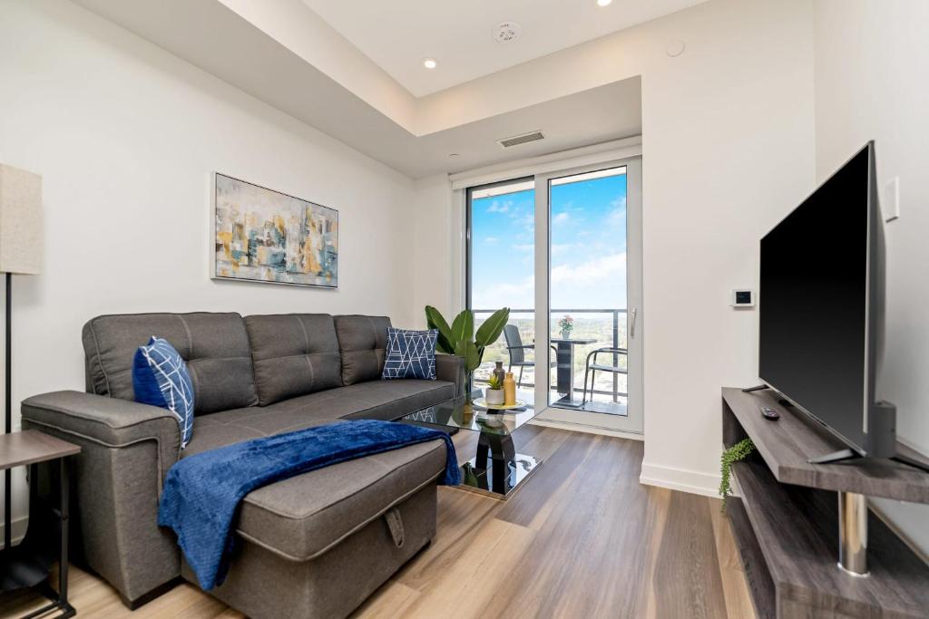 Modern 1BR King Bed Condo - Private Balcony في كيتشنر: غرفة معيشة مع أريكة وتلفزيون بشاشة مسطحة