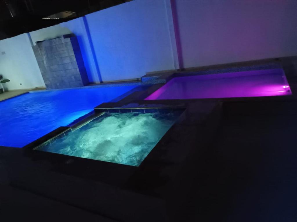uma grande piscina com iluminação azul e roxa em Vivienda Turística el Refugio em Villavicencio