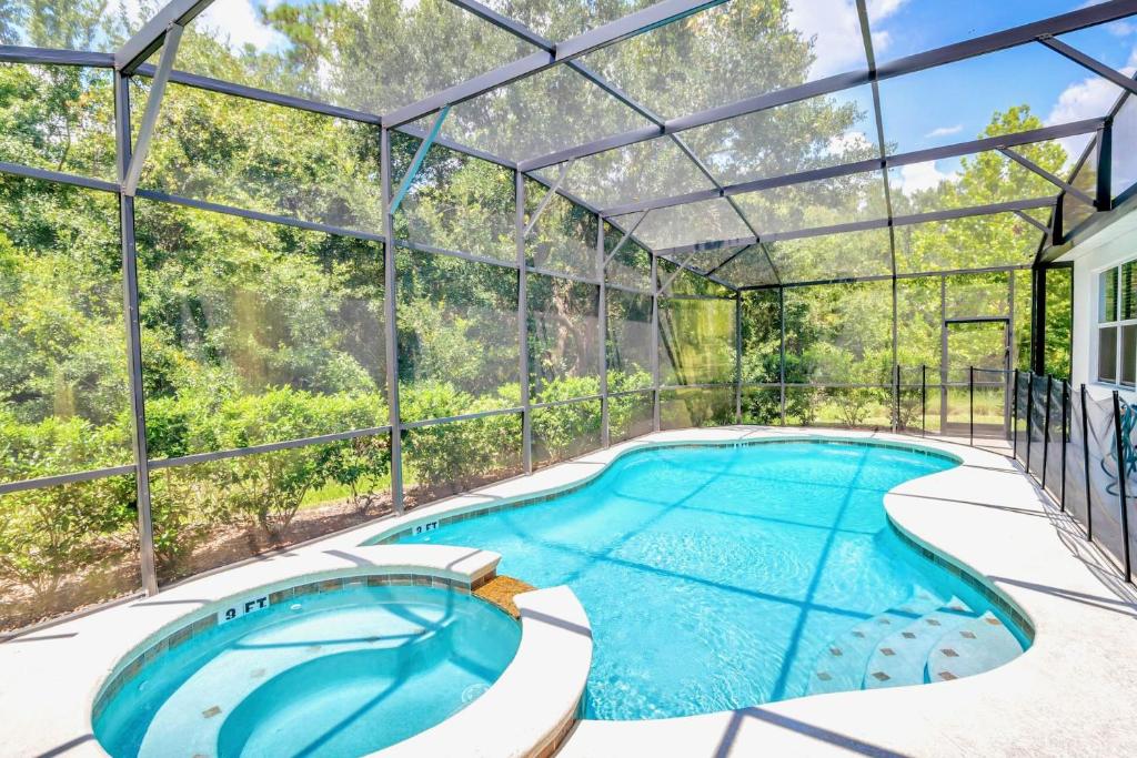 an indoor pool in a glass house with a swimming pool at Modern 6BR Home - Pool BBQ Hot Tub - Near Disney in Kissimmee