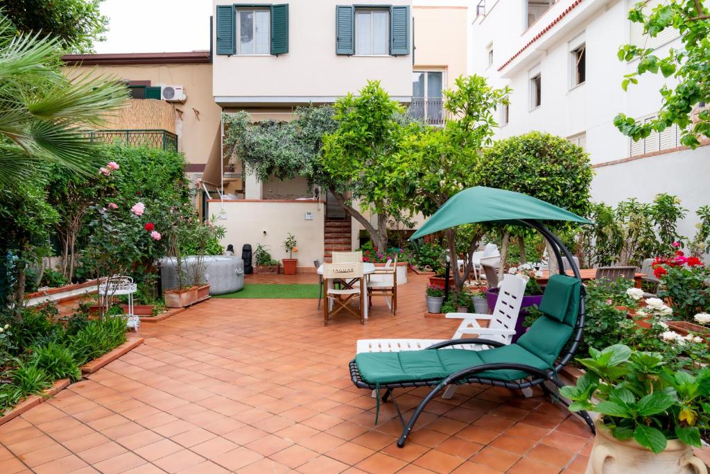 un patio con una silla verde y una sombrilla en MONDELLO COTTAGE en Mondello