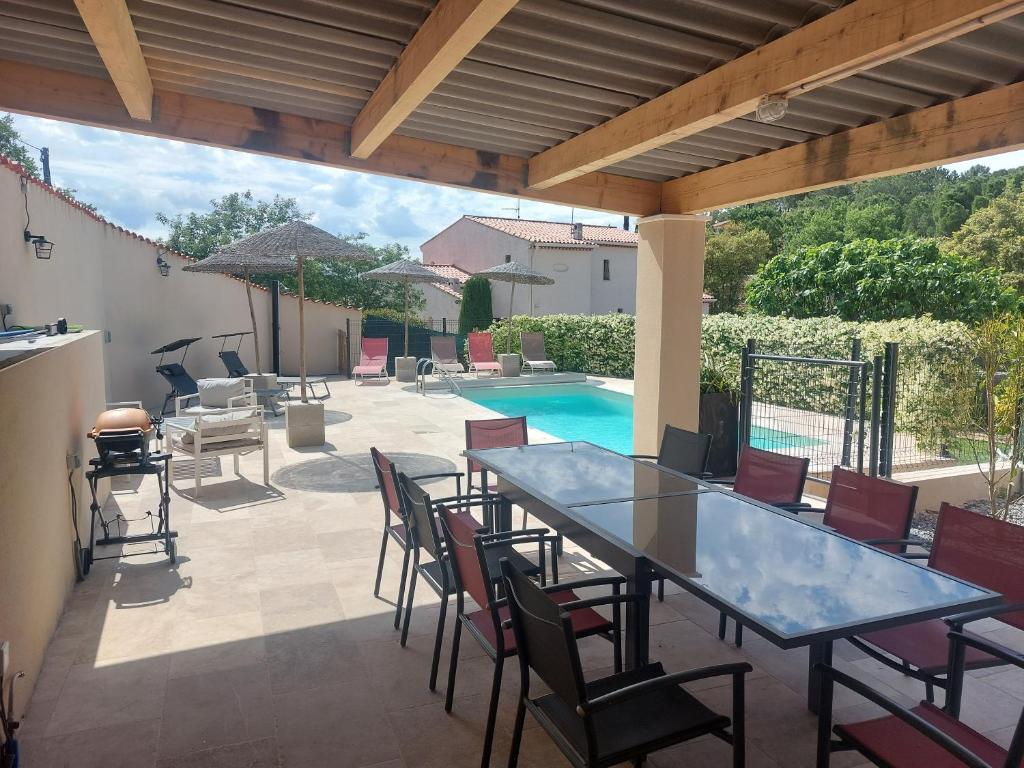 a patio with a table and chairs and a pool at Villa CALLY, chez MARIUS in Vidauban
