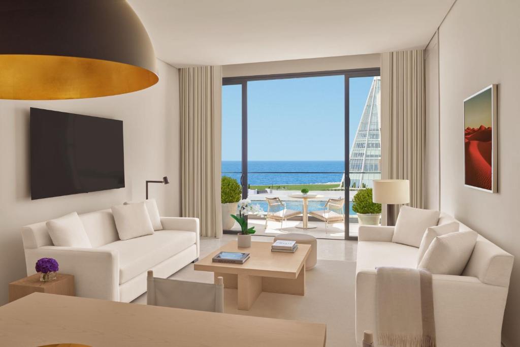 un soggiorno con mobili bianchi e vista sull'oceano di The Jeddah EDITION a Gedda