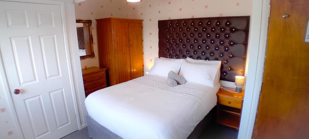 Un dormitorio con una cama blanca con cabecero de madera. en Home and Away near the Spa, en Bridlington