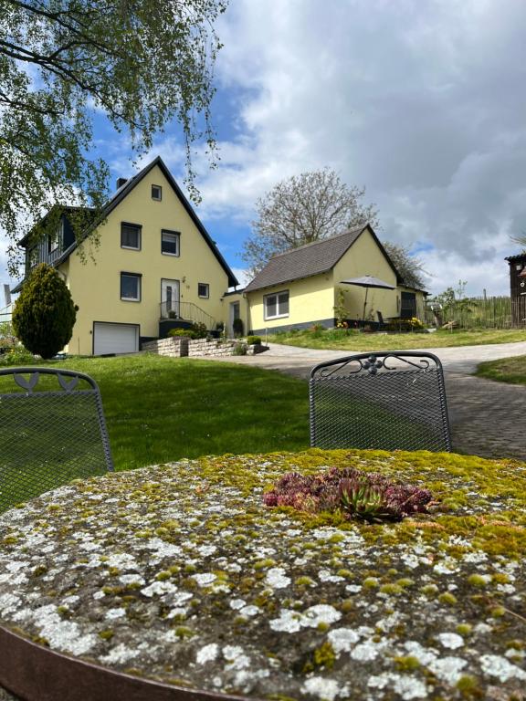 a house with a flower bed in the yard at Fewo Haus Hutzelbuck in idyllisch-grüner Lage nähe AN in Ansbach