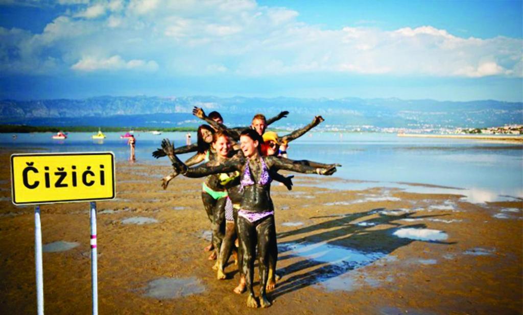 a group of people walking on the beach at Otok Krk Apartments in Čižići