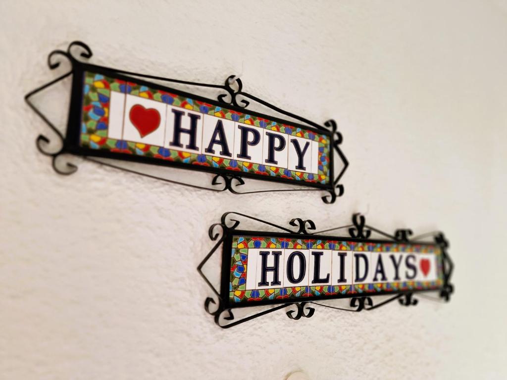 ein Schild mit der Aufschrift „Frohe Feiertage“, das an einer Wand hängt in der Unterkunft Happy in Holiday Miraflores Apartments in Mijas