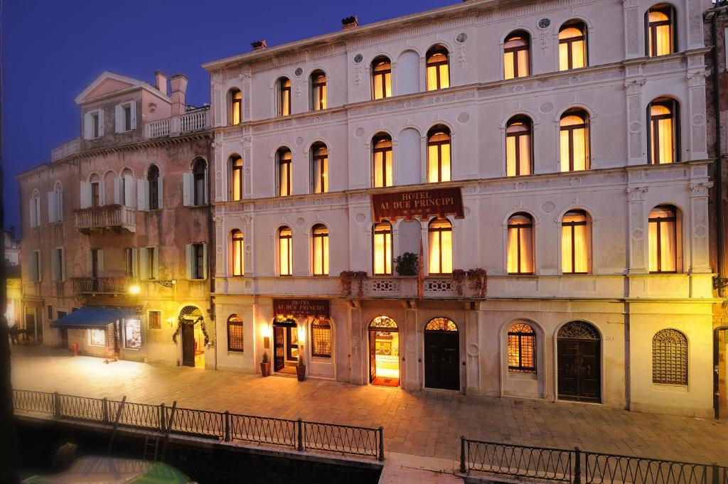 un gran edificio con sus luces encendidas por la noche en Hotel Ai Due Principi, en Venecia