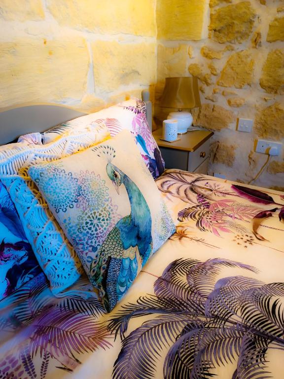 a bed with a colorful comforter and a table with a lamp at The LYNDEE HOUSE in Nadur