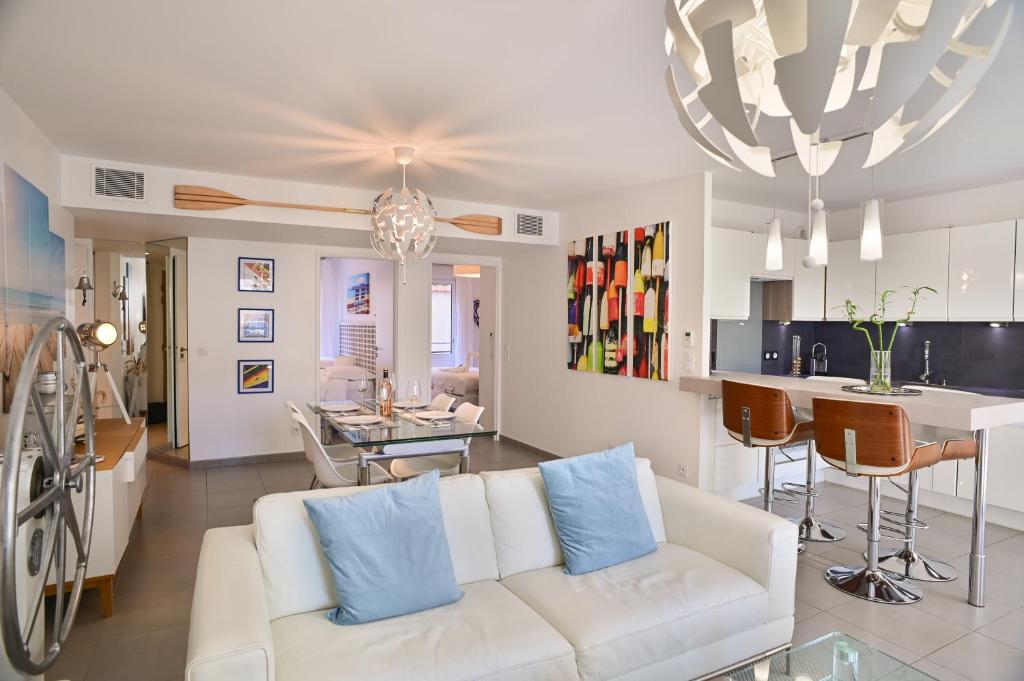 a living room with a white couch and a kitchen at Appartement de rêve avec terrasse et garage in Cannes