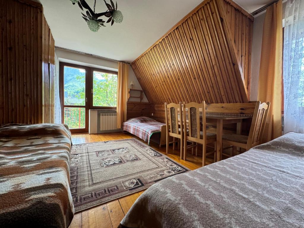une chambre avec deux lits et une table et des chaises dans l'établissement Pokoje Regle 30, à Zakopane