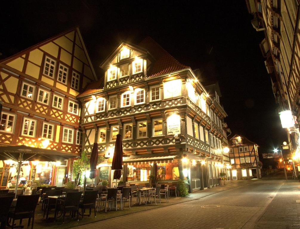 ein beleuchtetes Gebäude mit Tischen und Stühlen in der Nacht in der Unterkunft Fachwerk-Hotel Eisenbart in Hannoversch Münden