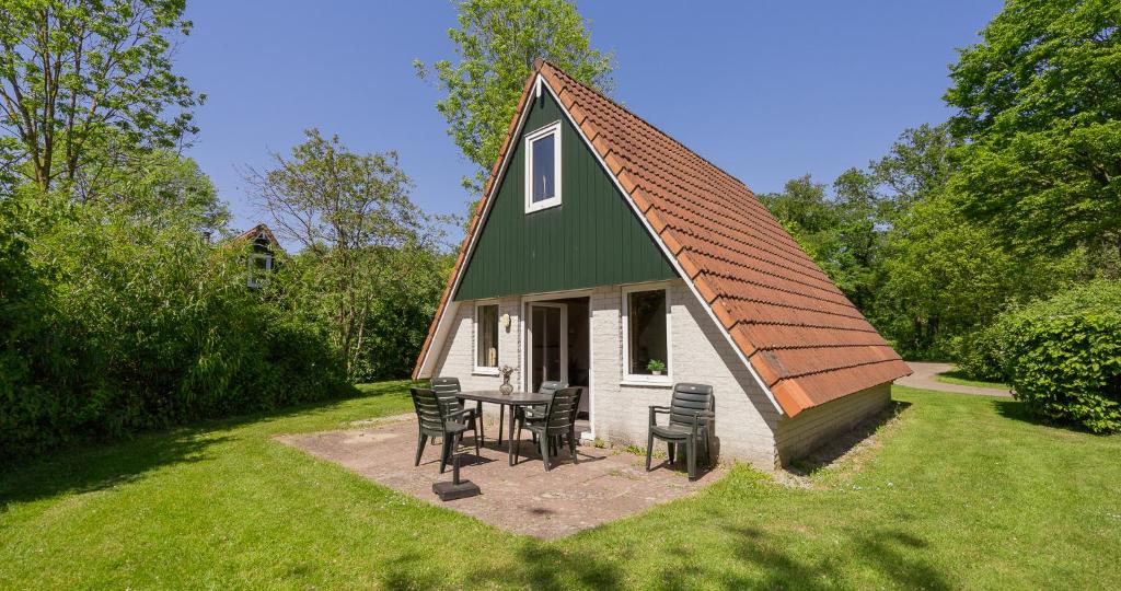 a small house with a table and chairs in the yard at Bungalows in het Holt in Gramsbergen
