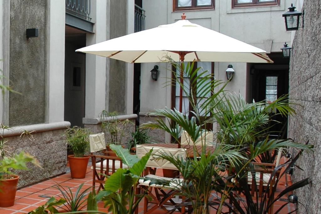 eine Terrasse mit einem Sonnenschirm, Tischen und Pflanzen in der Unterkunft Posada Gotan in Buenos Aires