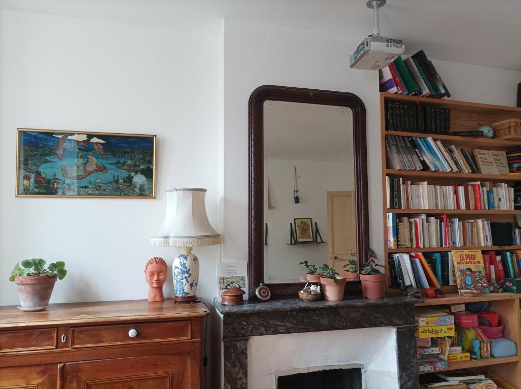 een woonkamer met een spiegel en een open haard bij Maison familiale en centre-ville in Rochefort