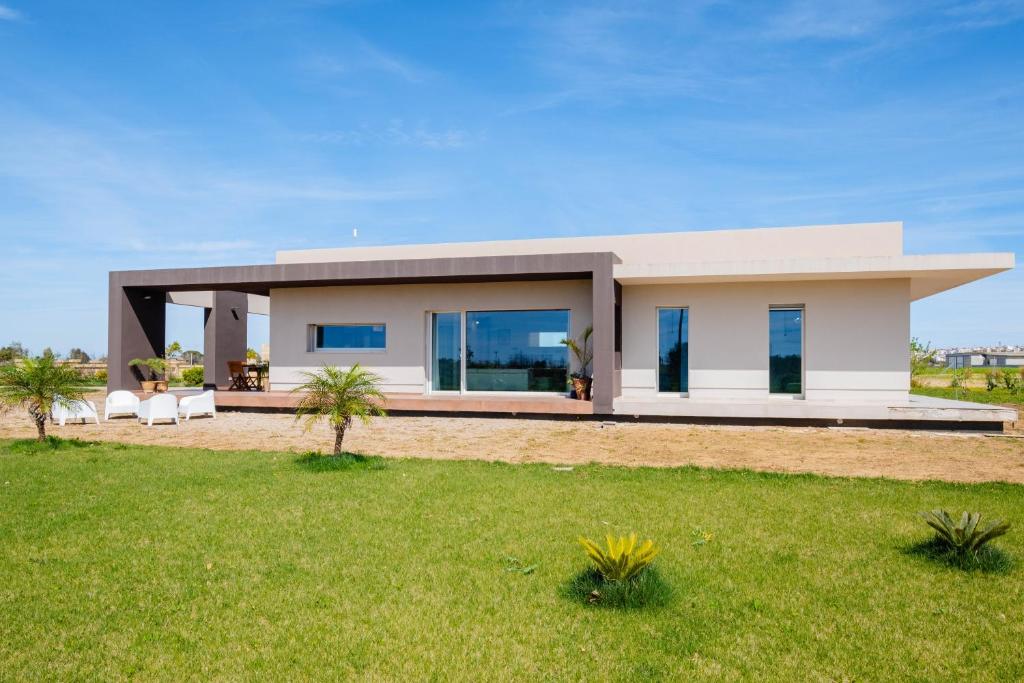 a house on the beach with a green lawn at Villa Medea in Casarano
