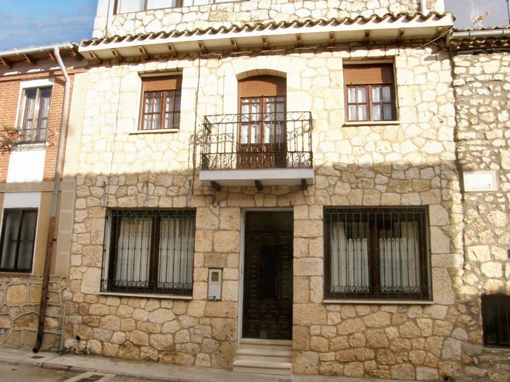 - un vieux bâtiment en pierre avec un balcon et une porte dans l'établissement 5 bedrooms house with city view and terrace at Banos de Valdearados, à Baños de Valdearados