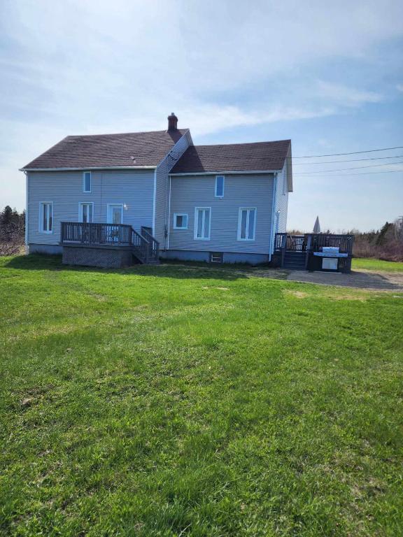 duży niebieski dom z dużym trawnikiem w obiekcie Oasis de la Baie w mieście Port-Daniel
