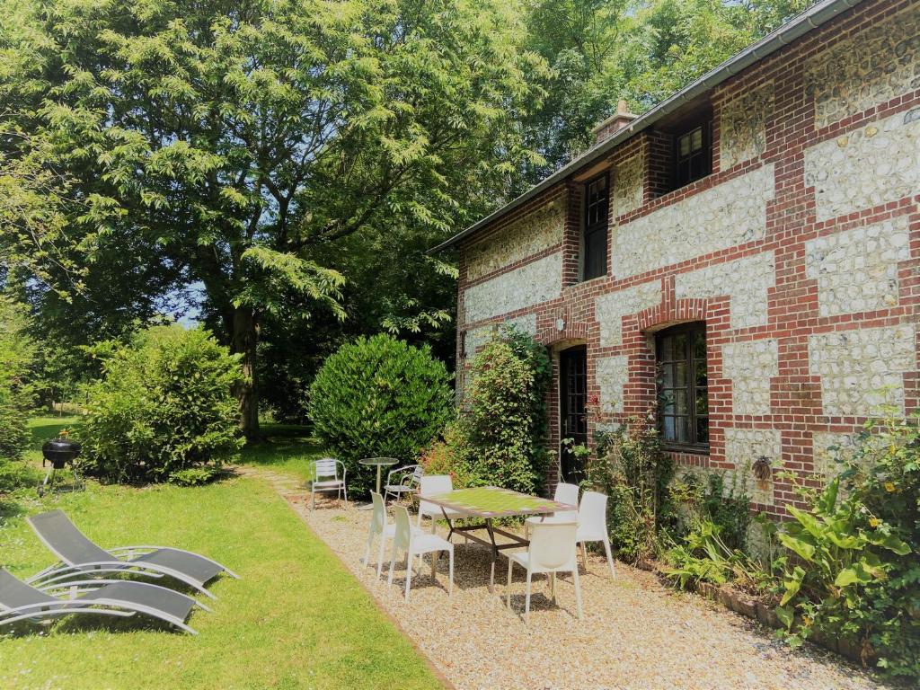 d'une terrasse avec des tables et des chaises à côté d'un bâtiment en briques. dans l'établissement Charming Normandy House with sauna, apple orchard, short walk to the beach, à Vattetot-sur-Mer
