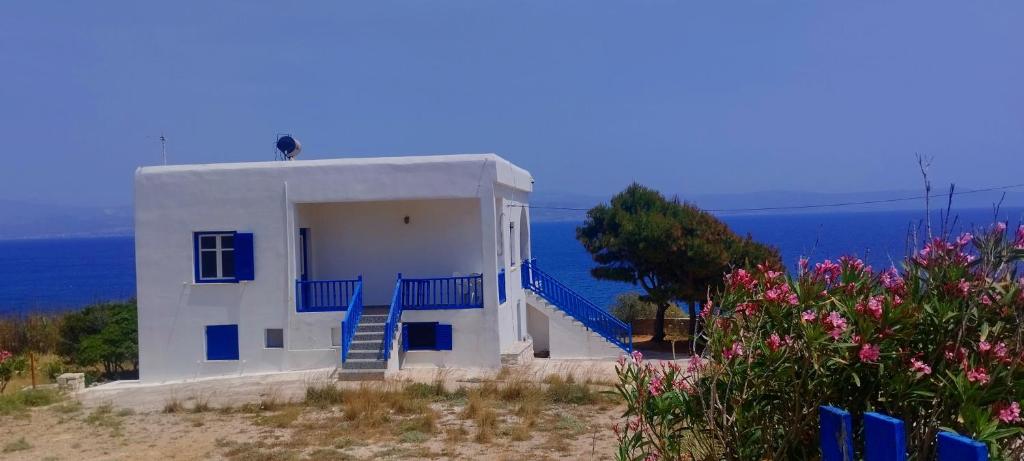 a white house with blue stairs on the side of the ocean at Καραμπεικο in Piso Livadi