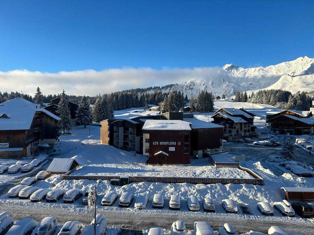 un complexe dans la neige avec une montagne en arrière-plan dans l'établissement Studio Praz de lys, à Taninges