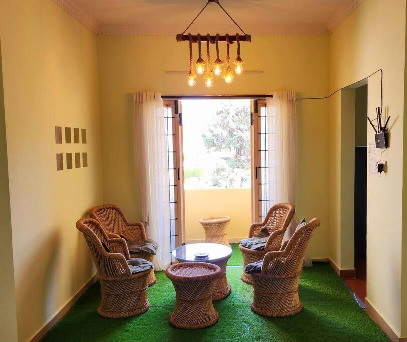 Zimmer mit Korbstühlen, einem Tisch und einem Fenster in der Unterkunft Spacious Greendale 3BHK Glam Apt in Bangalore