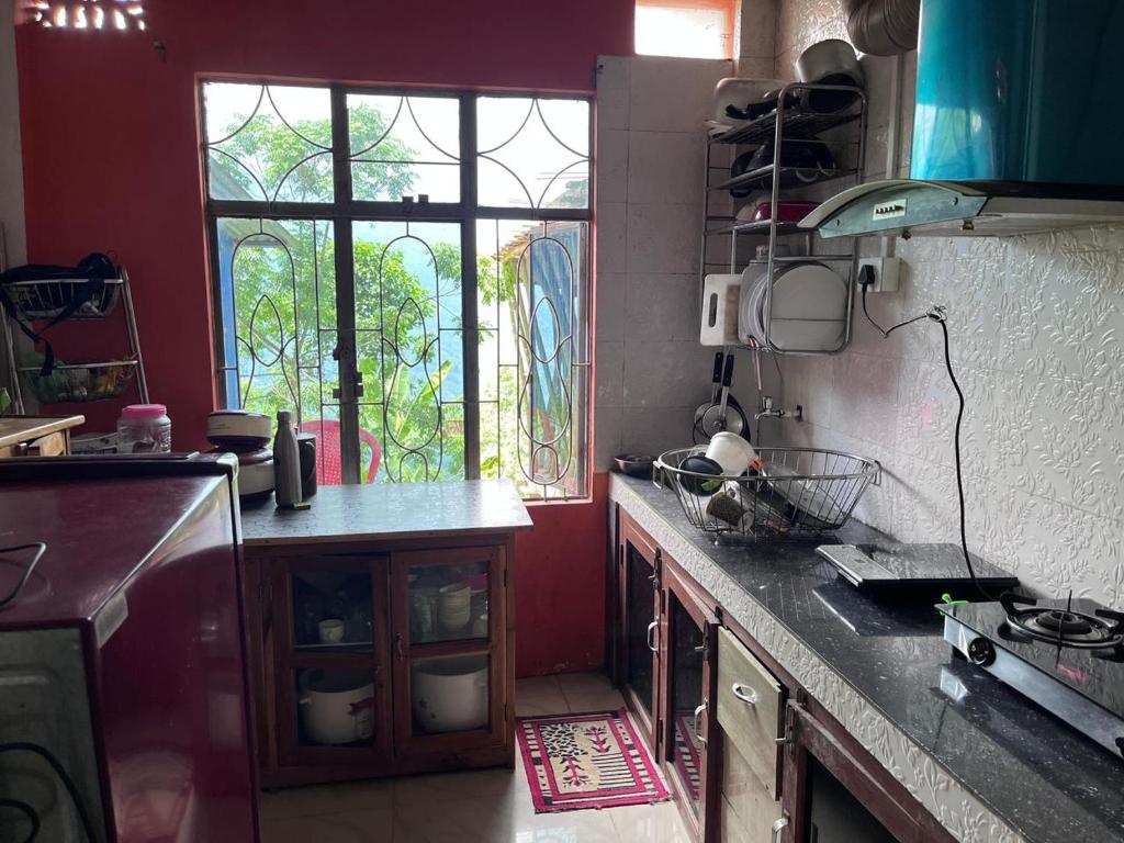 a kitchen with a counter top and a window at Happy Homestay Sittong in Mangpu