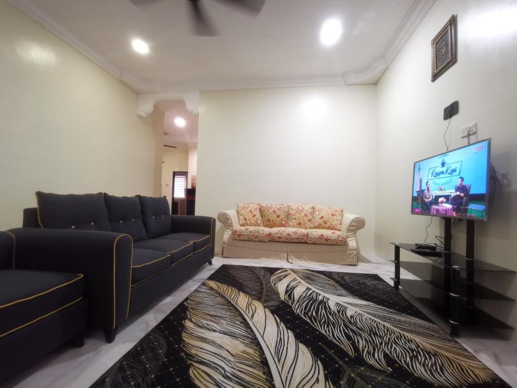 a living room with two couches and a flat screen tv at Kejora Guest House in Kuantan