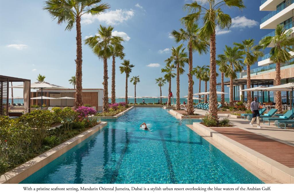 a swimming pool at a resort with palm trees at Mandarin Oriental Jumeira, Dubai in Dubai