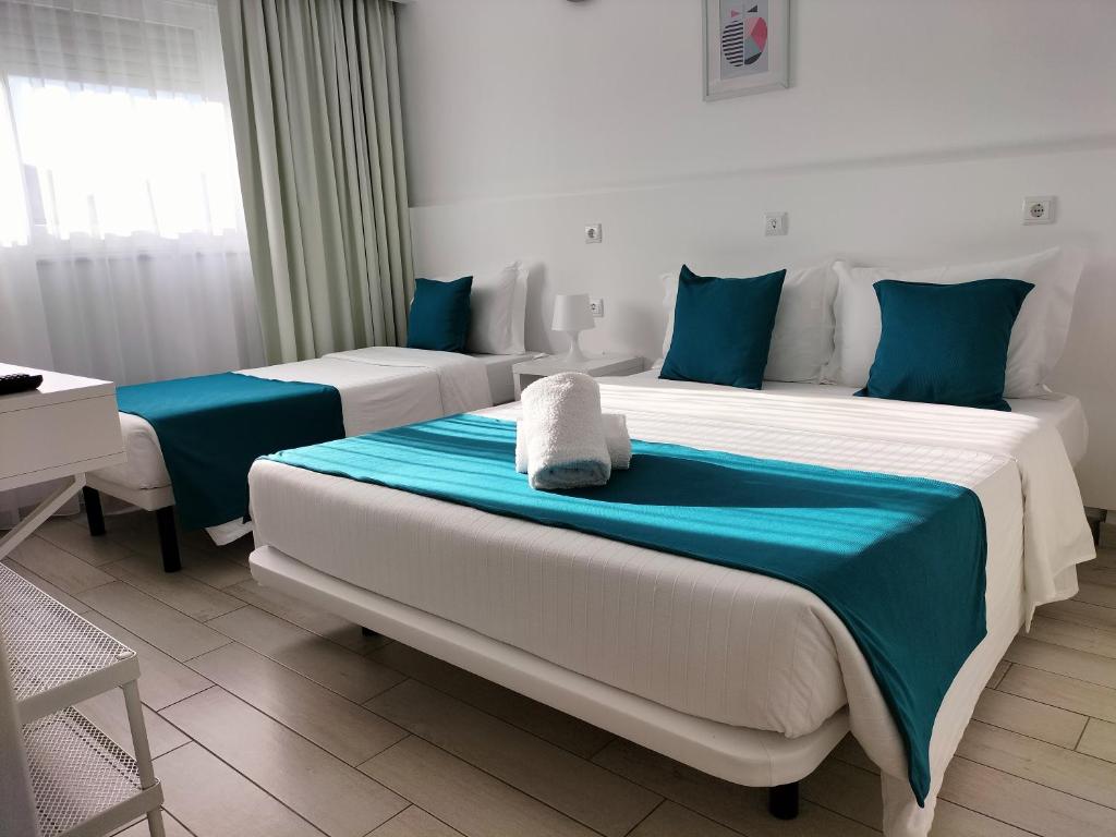two beds in a room with blue and white at Residencial Tropicália AL in Praia da Barra