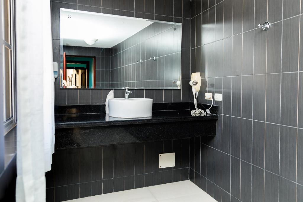 ein schwarzes Bad mit einem Waschbecken und einem Spiegel in der Unterkunft Hotel Brisa in Punta Cana