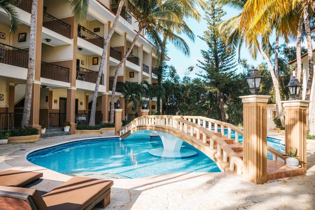 un puente sobre una piscina en un hotel con palmeras en Hotel Brisa en Punta Cana