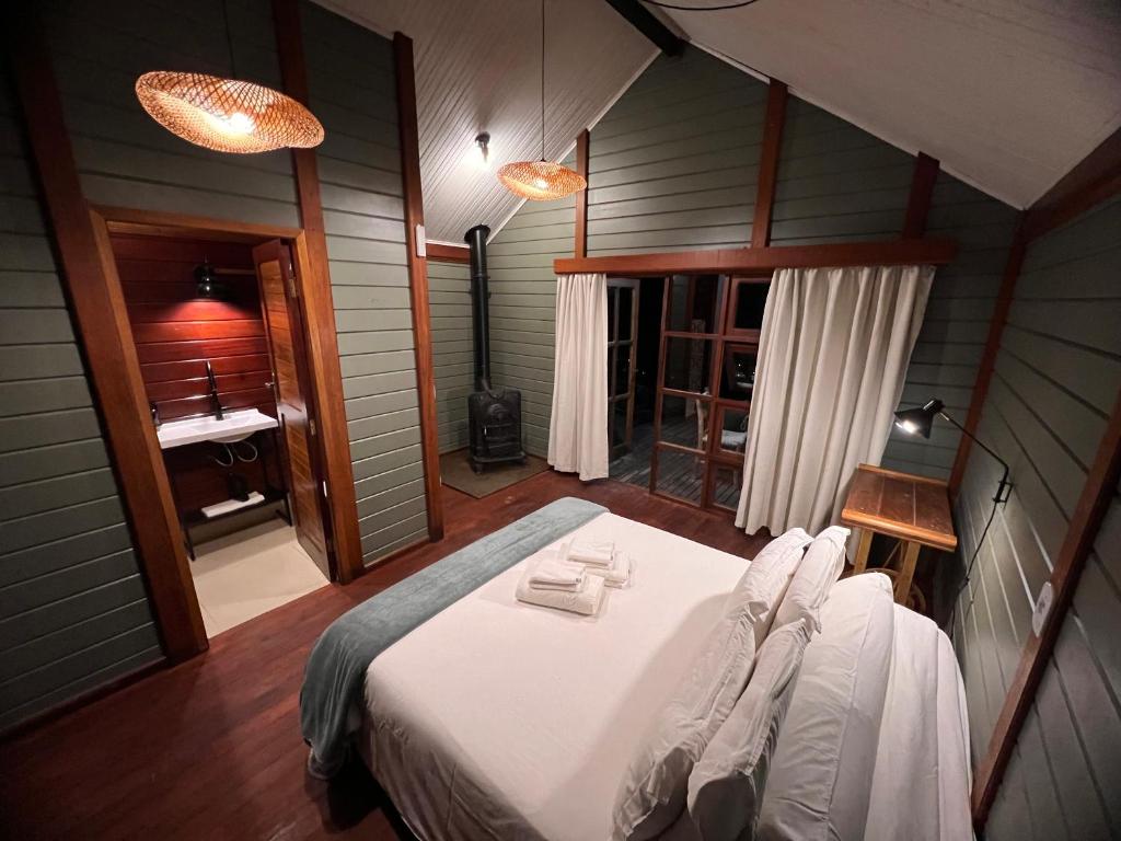 - une chambre avec un grand lit blanc dans l'établissement Reserva Santo Antônio, à Santo Antônio do Pinhal