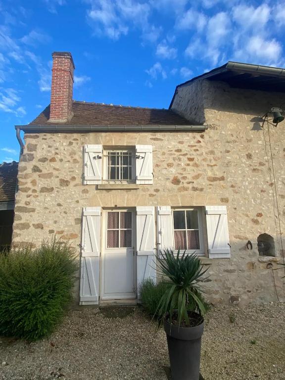 Cette ancienne maison en pierre est dotée de portes et de fenêtres blanches. dans l'établissement Appartement Duplex 2 pièces - Corps de ferme, à Montépilloy