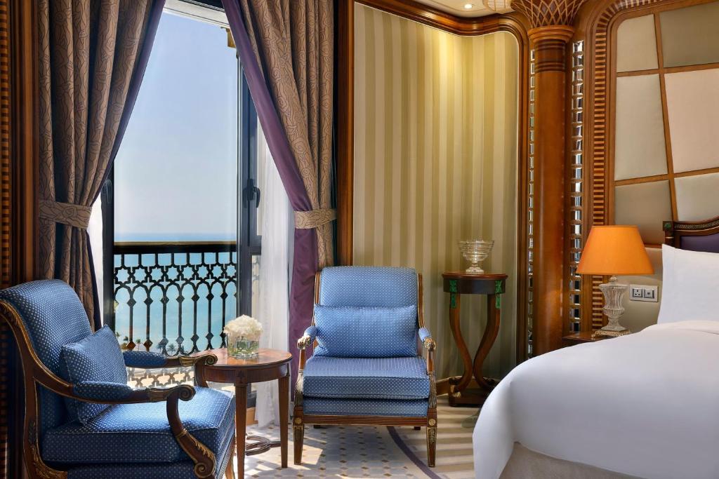a bedroom with two chairs and a bed and a balcony at The Ritz-Carlton Jeddah in Jeddah