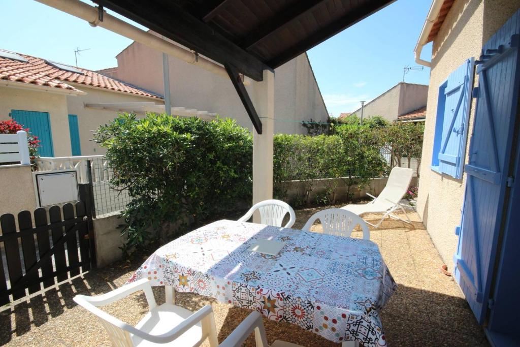 une table et des chaises assises sur une terrasse dans l'établissement Jolie maison d'angle, belle terrasse arborée et clôturée , 4 couchages, cuisine climatisée , à 400 m de la mer a PORTIRAGNES PLAGE LRHP58, à Portiragnes