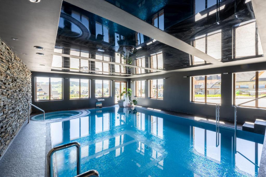 a swimming pool in a building with windows at Hotel Zawrat - KROK NA STOK! in Białka Tatrzanska