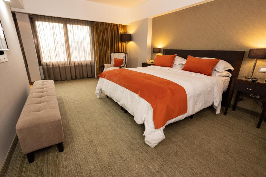 um quarto de hotel com uma cama grande com almofadas laranja em Libertador Hotel em Buenos Aires