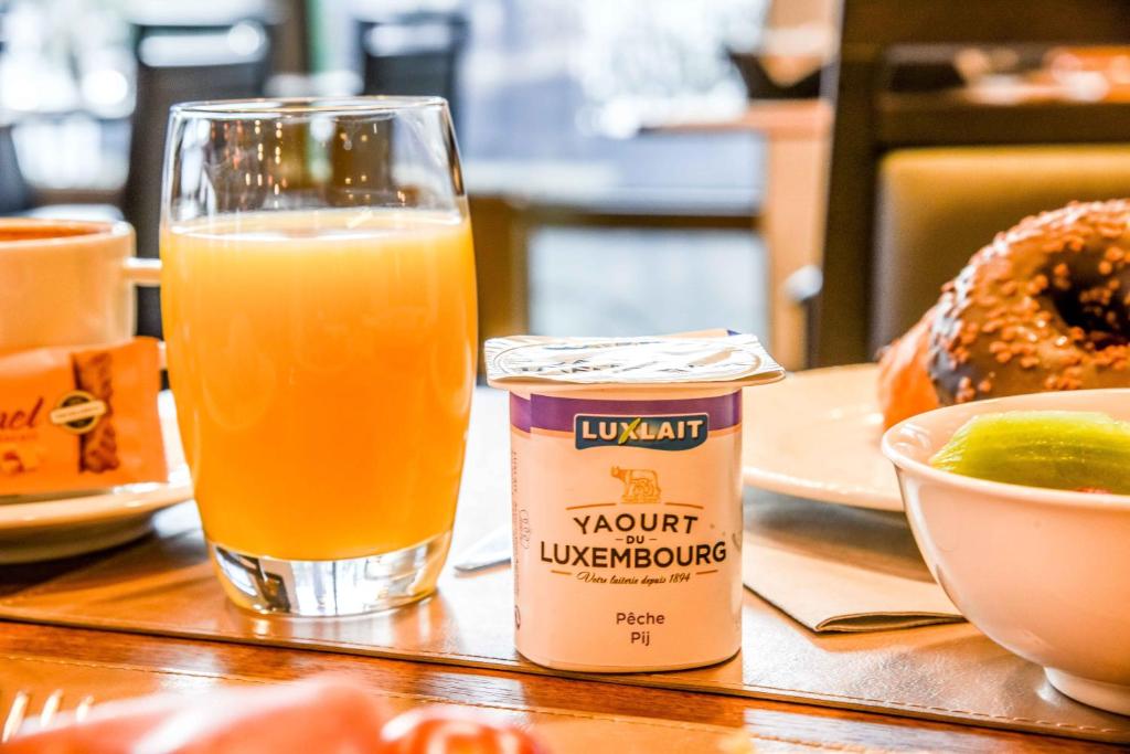 a glass of orange juice next to a cup of orange juice at Mandarina Hotel Luxembourg Airport in Luxembourg