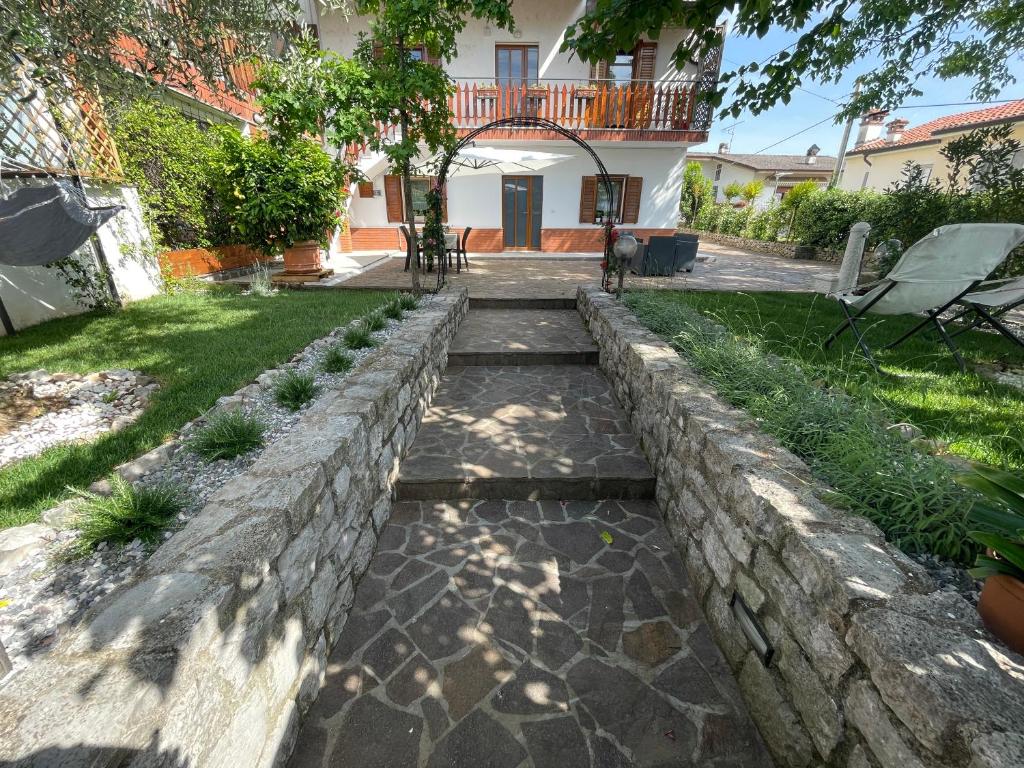 a garden with a stone retaining wall and a walkway at All'ombra del tiglio Bed&Breakfast in Doberdò del Lago