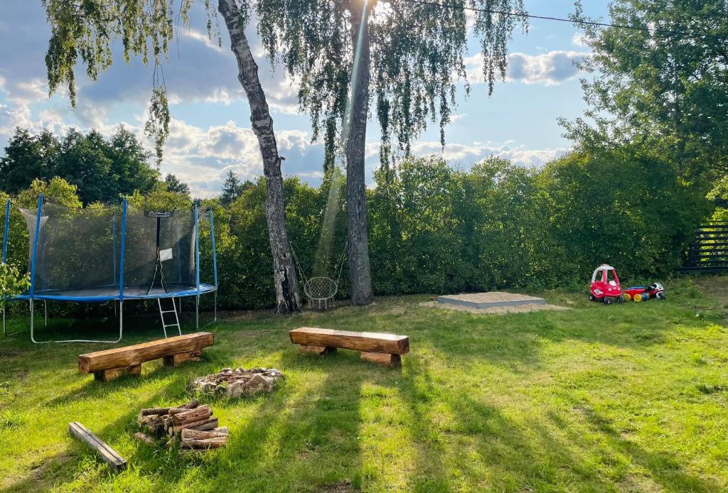 a park with two benches and a trampoline at Dom-na Mazury! in Mrągowo