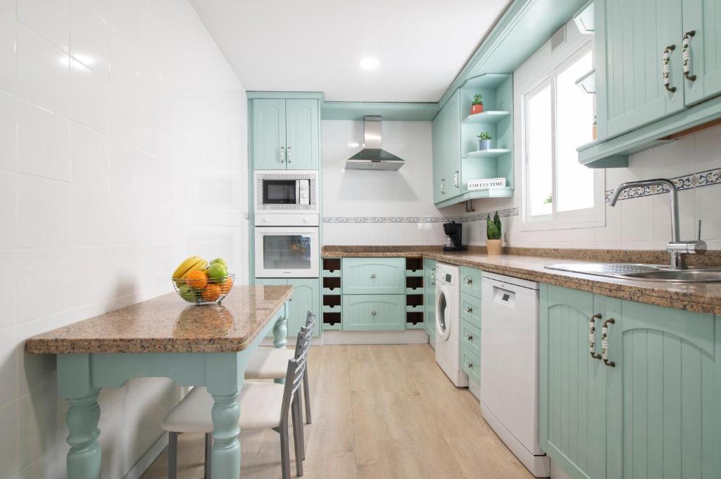 a kitchen with blue cabinets and a table with a bowl of fruit at Los Áticos in Estepona