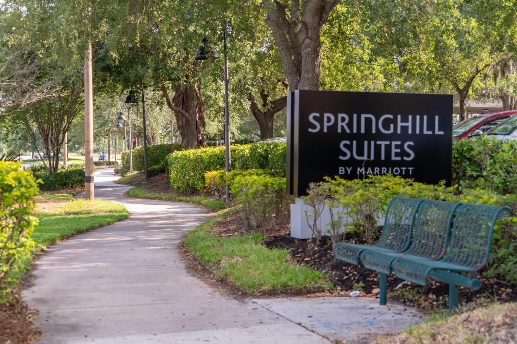 eine grüne Parkbank neben einem Schild für Springhill Suiten in der Unterkunft SpringHill Suites by Marriott Orlando Convention Center in Orlando