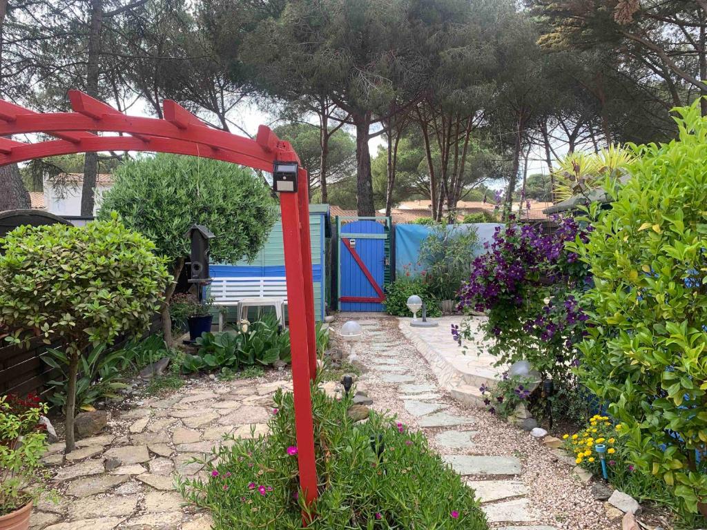 un jardin avec une tonnelle rouge et un banc dans l'établissement Appartement jardin Cap d'Agde, au Cap d'Agde