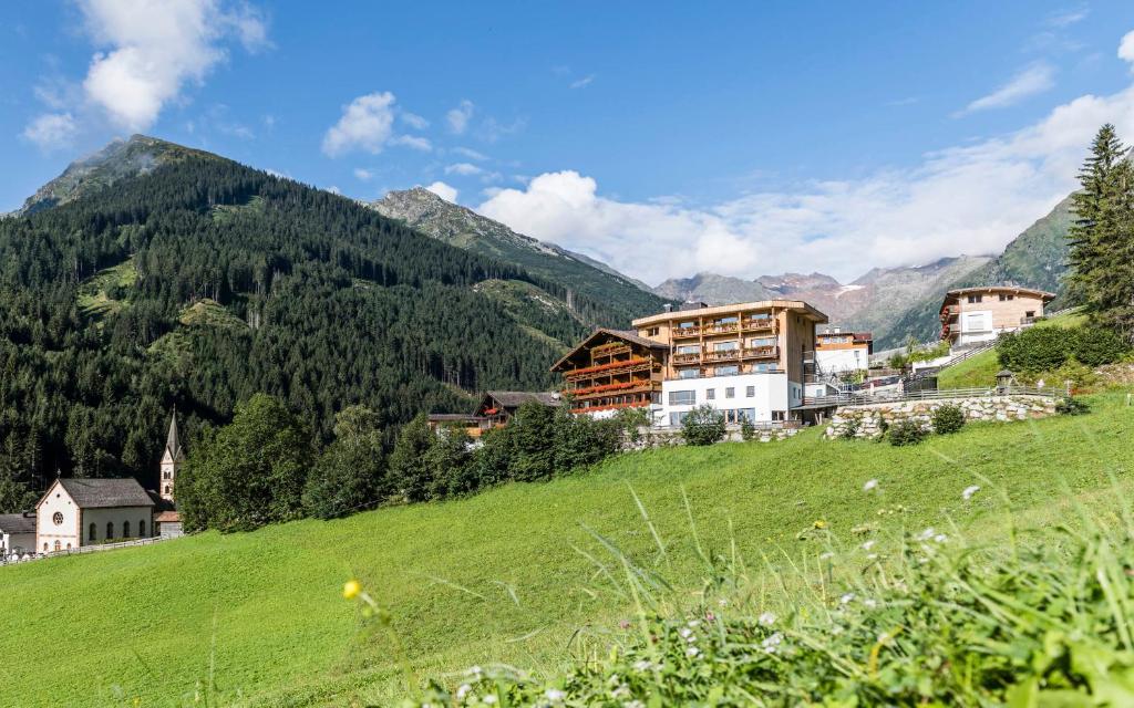 Ein Dorf auf einem Hügel mit Bergen im Hintergrund in der Unterkunft Hotel Panorama in Innerpflersch