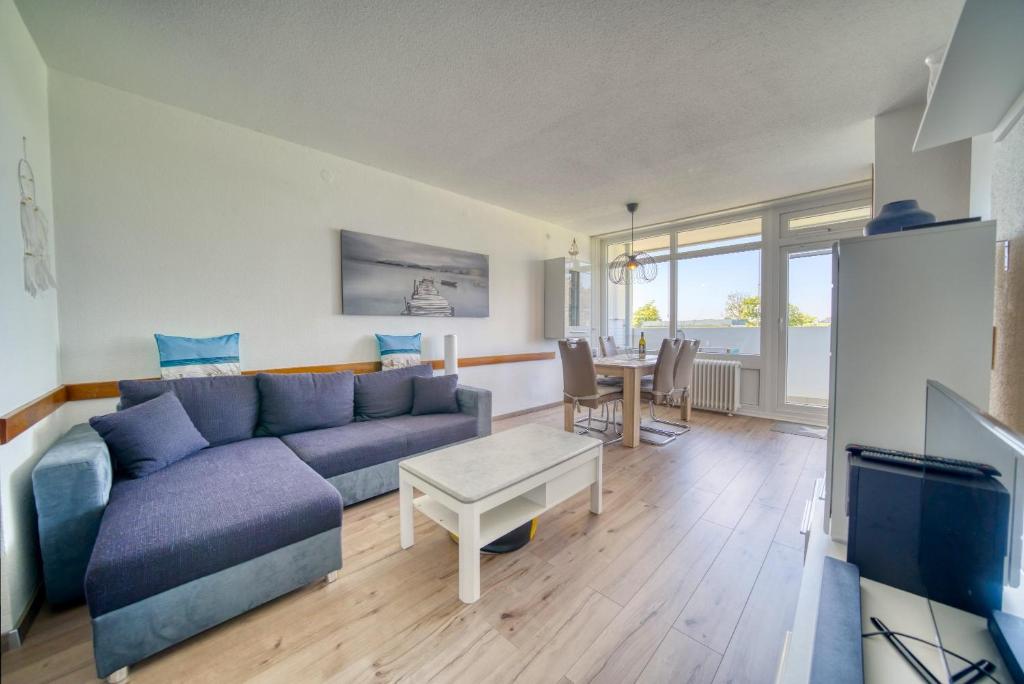 ein Wohnzimmer mit einem blauen Sofa und einem Tisch in der Unterkunft Ferienpark - Haus F, App 0FEG01 in Heiligenhafen