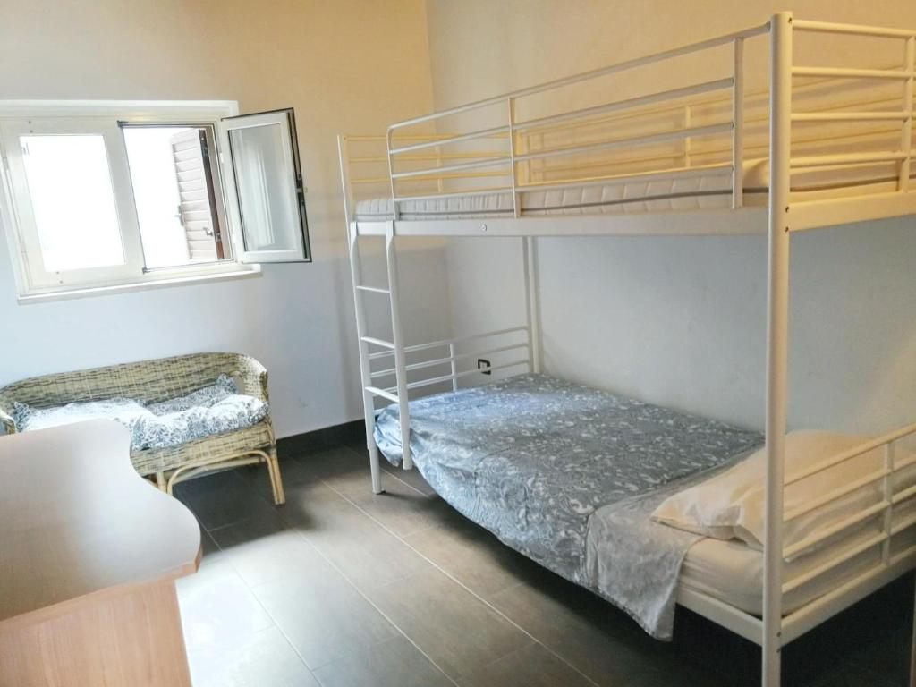 um quarto com 2 beliches e uma cadeira em 2 bedrooms apartement with furnished balcony and wifi at Casalvecchio Siculo 6 km away from the beach em Casalvecchio Siculo