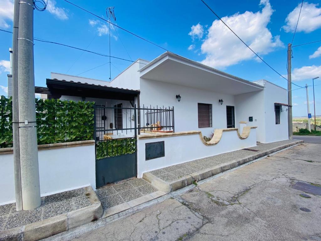 una casa blanca con un seto verde en Mandorli in fiore, en Ugento